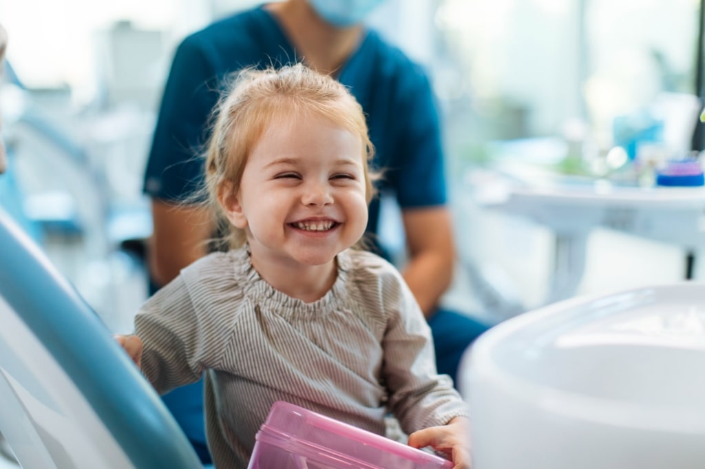 Smiling child sitting in a dentist chair preparing for a visit