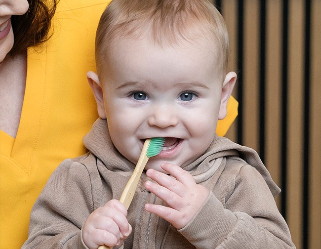 Baby holding toothbrush in mouth